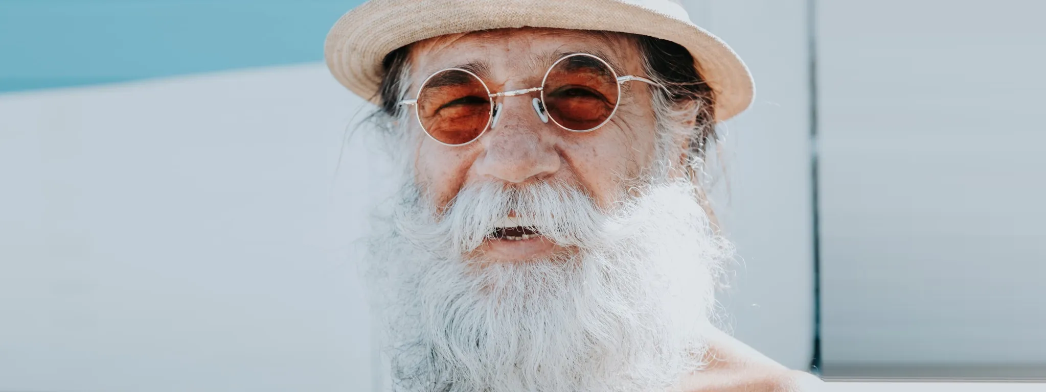 Homme retraité souriant avec des lunettes de soleil et un chapeau, illustrant la retraite paisible à l’étranger.