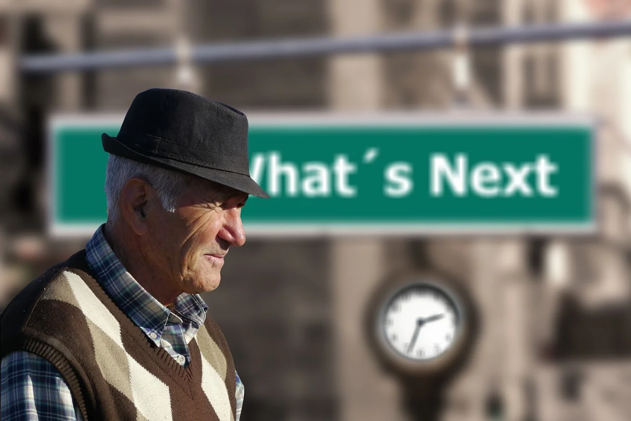 Homme âgé devant un panneau "What’s Next", illustrant l’anticipation et la planification financière pour la retraite par capitalisation.