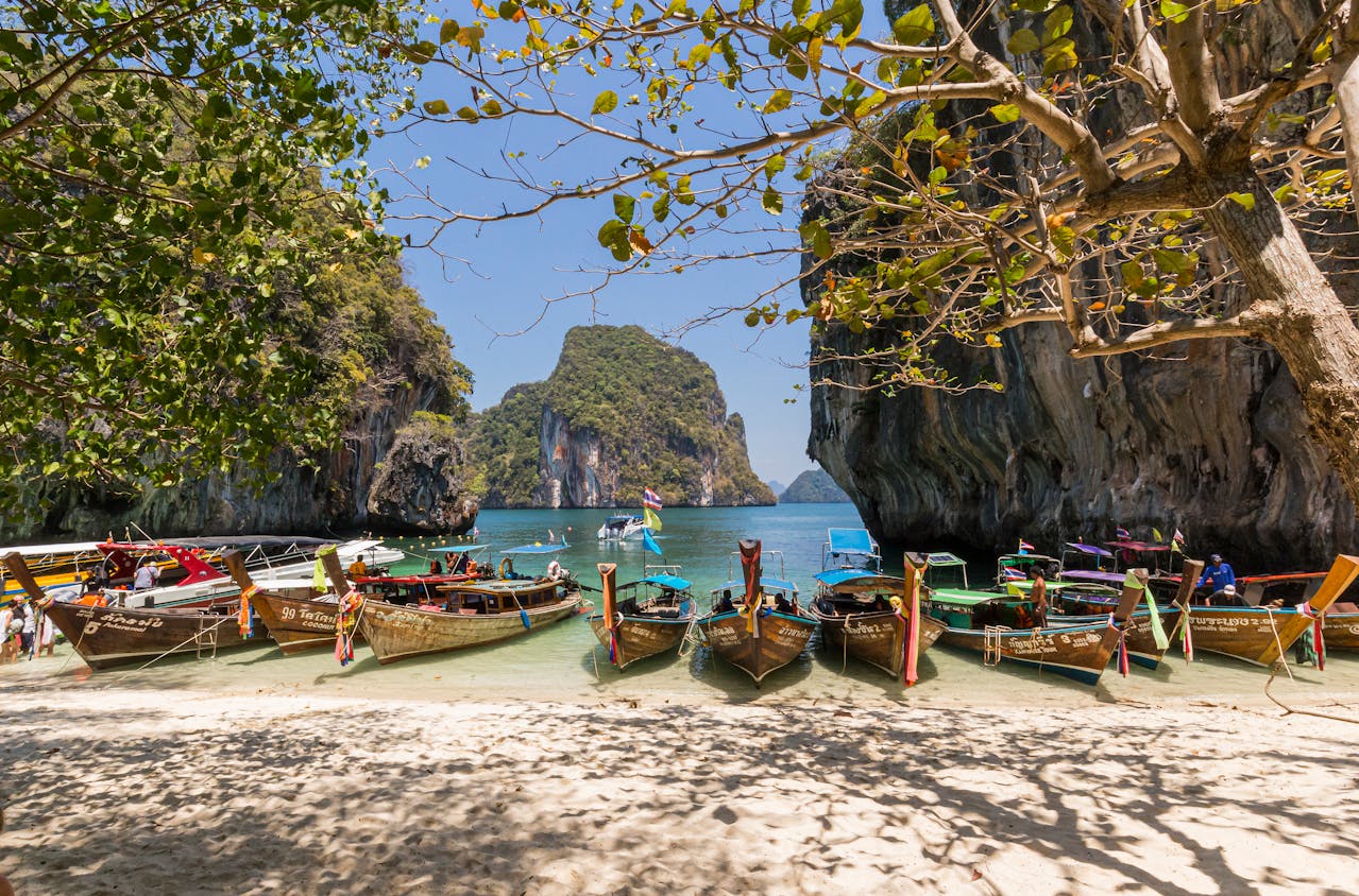 Bateaux traditionnels sur une plage de Thaïlande, illustrant le cadre idyllique pour une retraite sereine et ensoleillée.