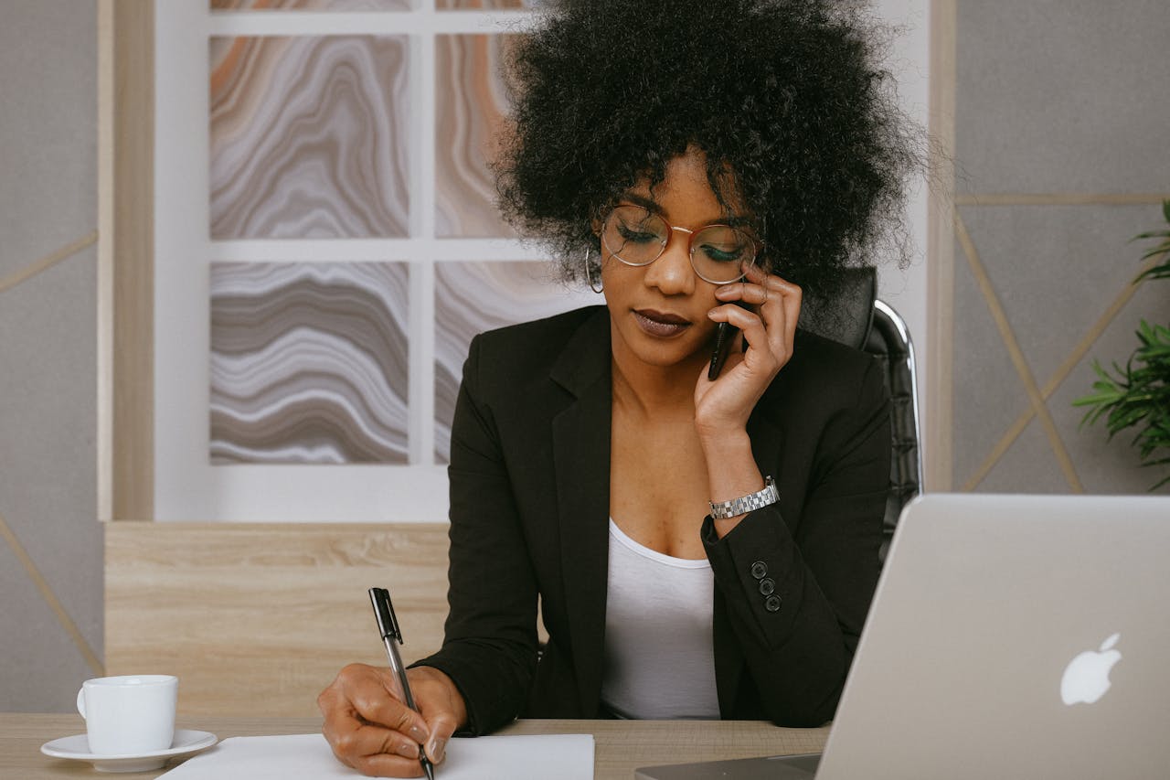 Femme en blazer noir tenant un smartphone, symbolisant la souscription en ligne à une assurance vie luxembourgeoise.