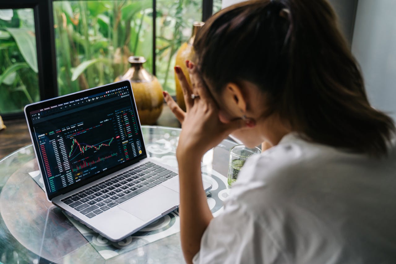 Femme analysant des graphiques d'actions sur un ordinateur, illustrant le trading en ligne pour expatriés et non-résidents.