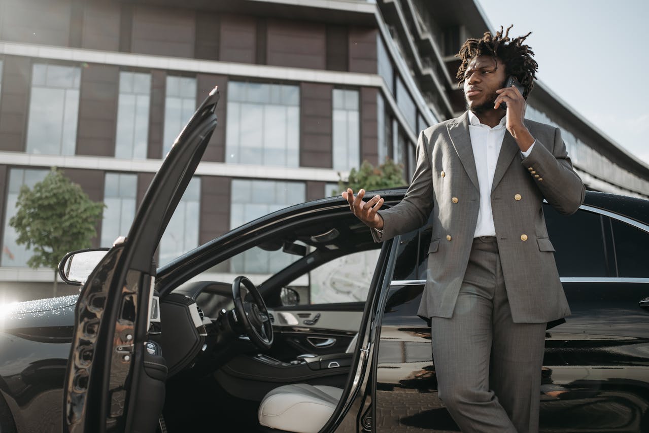 Homme en costume au téléphone près d’une voiture, illustrant l’attente ou la gestion des démarches pour récupérer des fonds d’assurance vie.