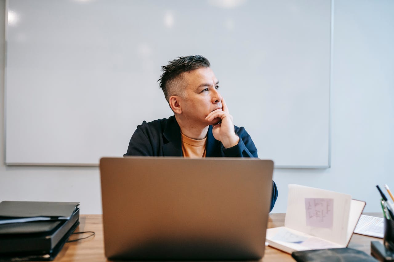 Homme pensif regardant par la fenêtre, illustrant la réflexion avant de clôturer un contrat d’assurance vie.