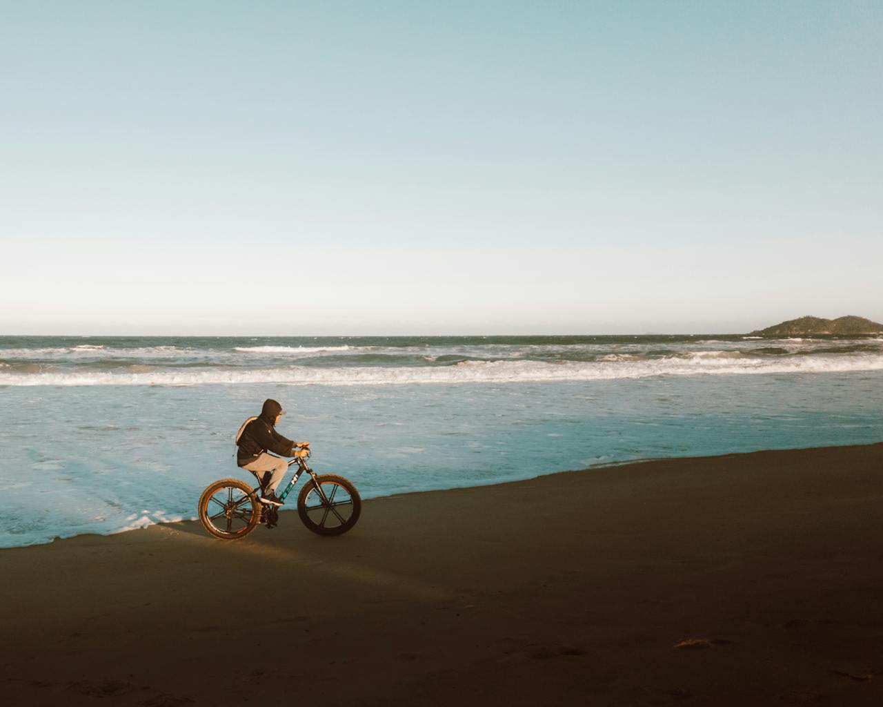 Cycliste sur une plage au coucher du soleil, illustrant la liberté de l’expatriation et la nécessité d’une bonne assurance santé à l’étranger.