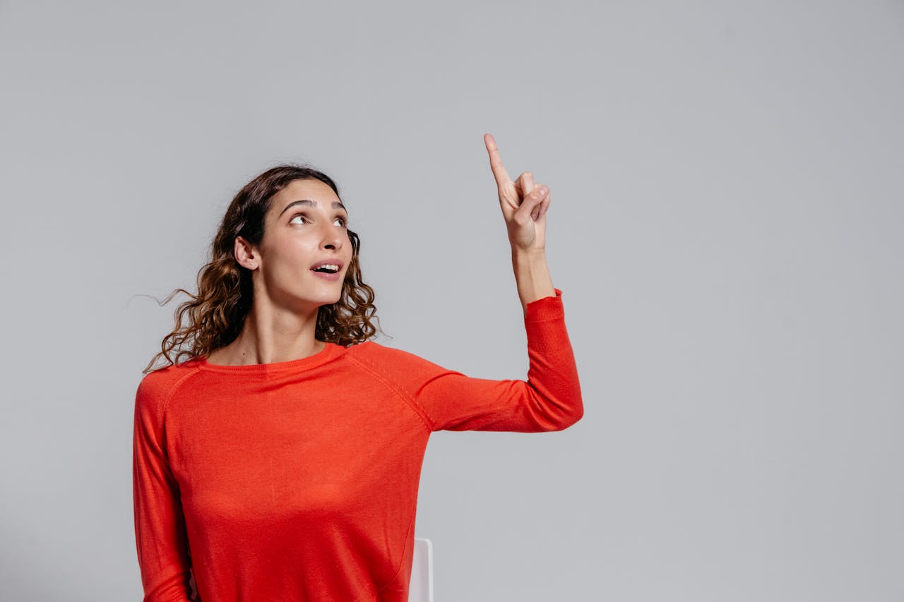 Femme en chemise rouge réfléchissant, illustrant le choix entre assurance vie et compte-titres pour investir.