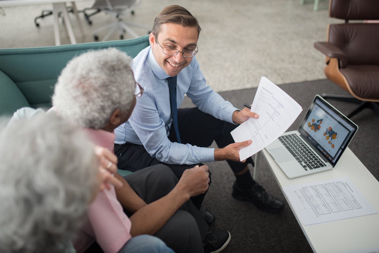 Un conseiller montre des documents à un couple de retraité, illustrant la compréhension des différences entre retraite par répartition, annuités et points.