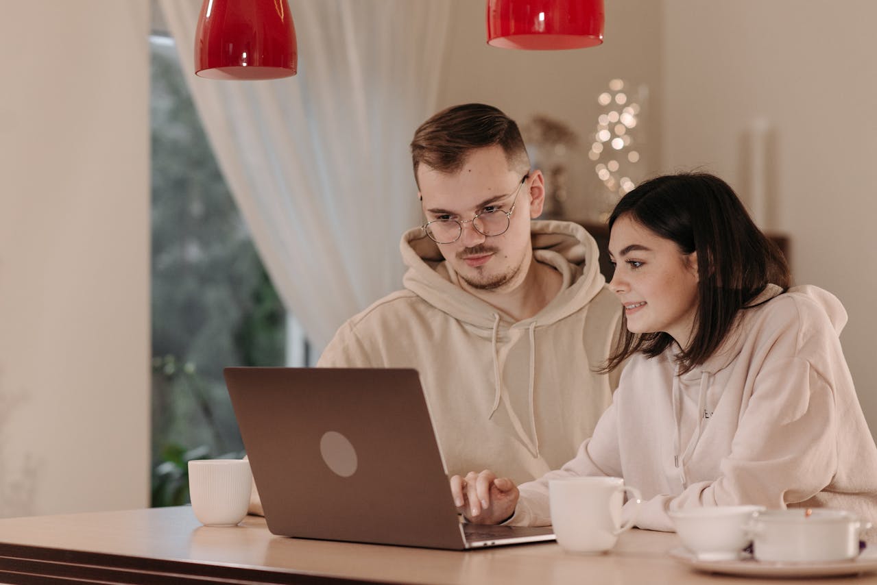 Couple consultant un ordinateur portable, illustrant la recherche d’informations sur les placements FIP et FCPI pour optimiser ses investissements.