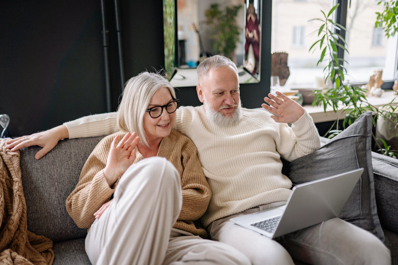 Couple de seniors assis sur un canapé, illustrant la sérénité et la planification financière offertes par un contrat d’assurance vie.