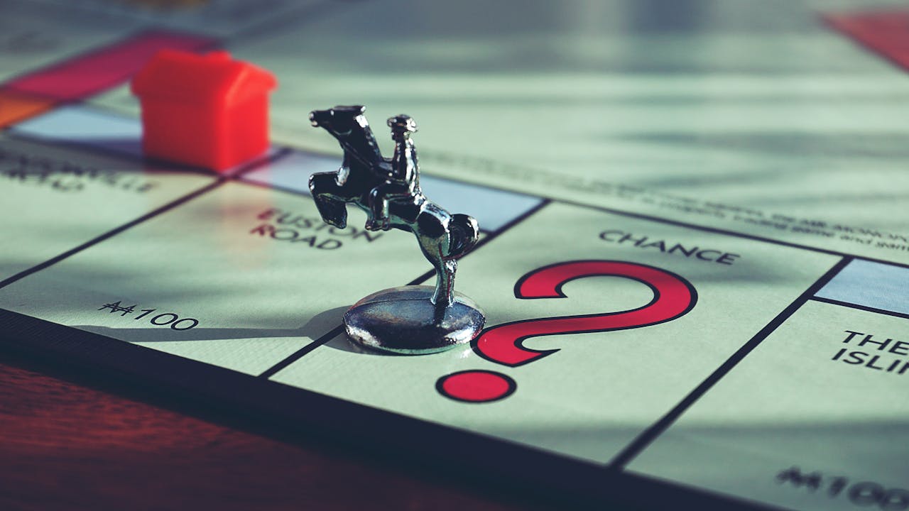Pion de maison posé sur un plateau de Monopoly, illustrant la question du devenir de la résidence principale après une expatriation.
