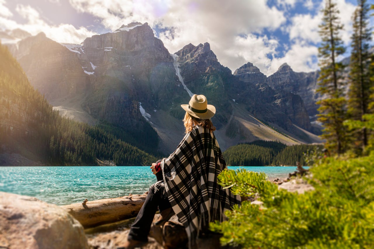 Femme assise sur un rocher face à un lac, illustrant la réflexion et la sérénité liées à la gestion patrimoniale internationale des expatriés.