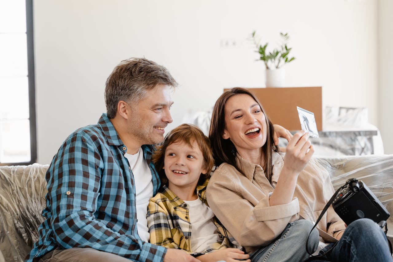 Homme et femme souriants tenant un smartphone, symbolisant la communication et la transmission intergénérationnelle du patrimoine familial.