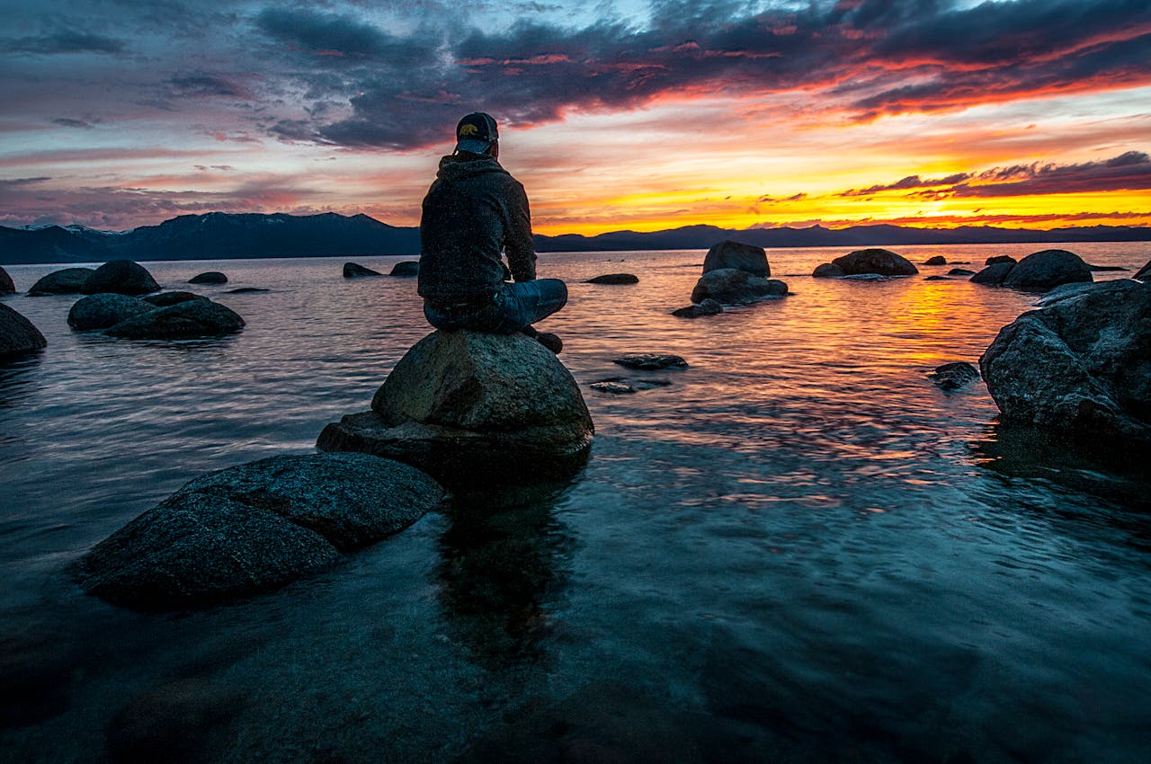 Personne assise sur un rocher face à la mer, symbolisant l’expatriation et les démarches fiscales liées aux prélèvements sociaux.