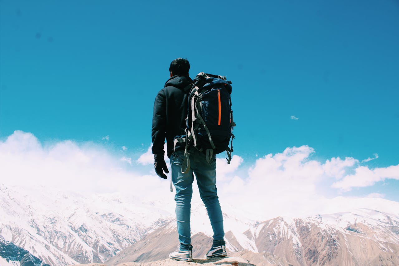 Homme debout sur une montagne face à l’horizon, symbolisant la prise de hauteur et la stratégie d’investissement entre PEA et CTO pour expatriés.