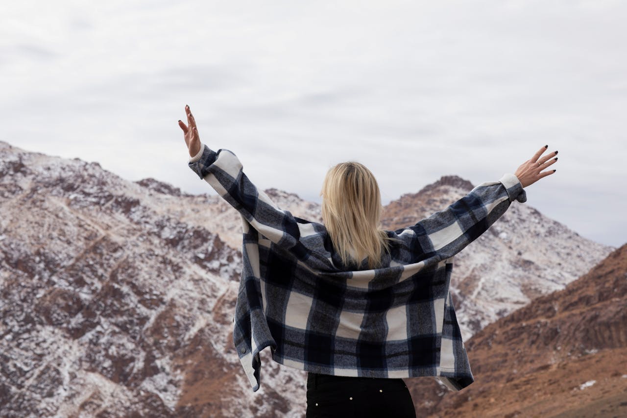Femme de dos en chemise à carreaux observant un paysage naturel, illustrant une réflexion personnelle et le choix entre assurance vie Luxembourg ou France.