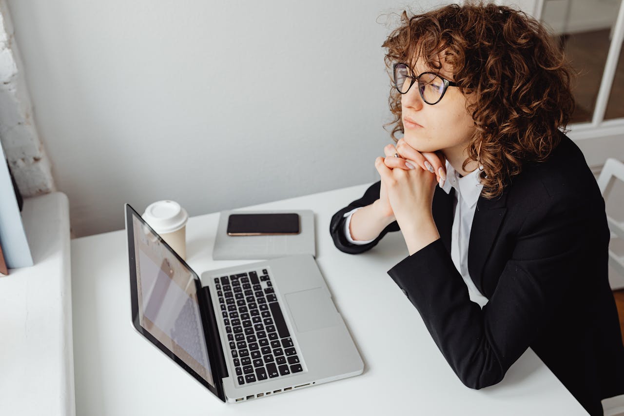 Femme en blazer noir utilisant un MacBook Pro, illustrant l’analyse de SCPI en direct ou via assurance-vie.