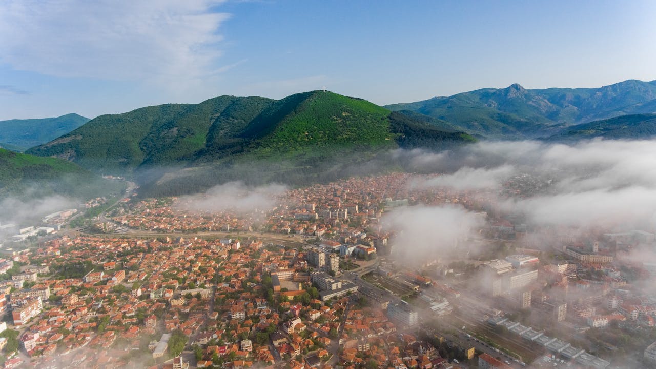Ville bulgare entourée de montagnes sous la brume, illustrant l’expatriation en Bulgarie et le choix d’une assurance vie adaptée.