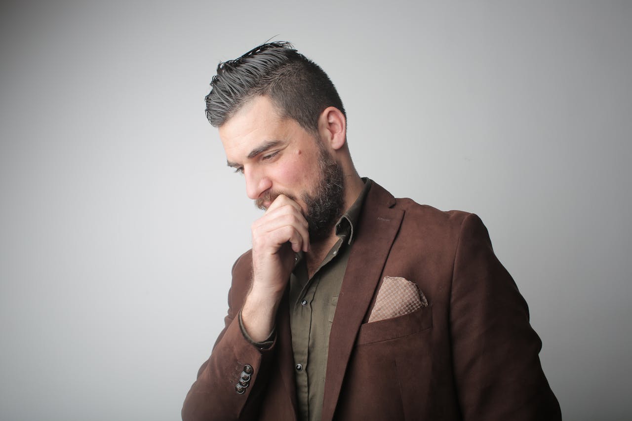 Homme pensif en manteau marron, illustrant la réflexion entre assurance vie et contrat de capitalisation luxembourgeois.