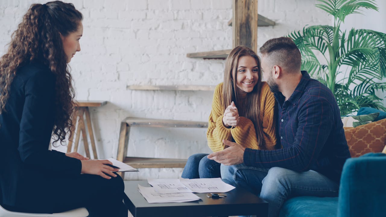 Couple échangeant avec un conseiller en bureau, illustrant la consultation d’un conseiller en gestion de patrimoine.