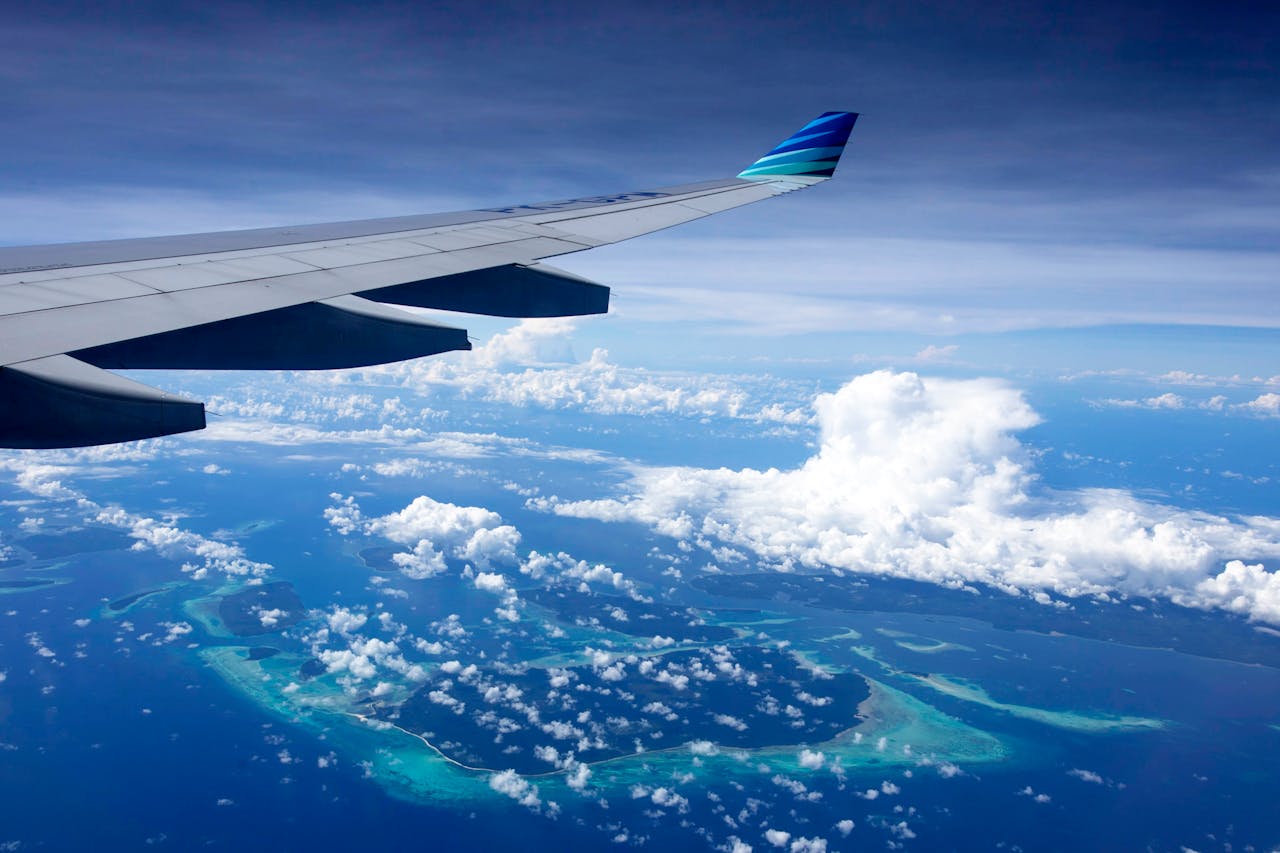 Vue aérienne d’îles et de nuages depuis un avion pour illustrer l’assurance vie selon le pays d’expatriation