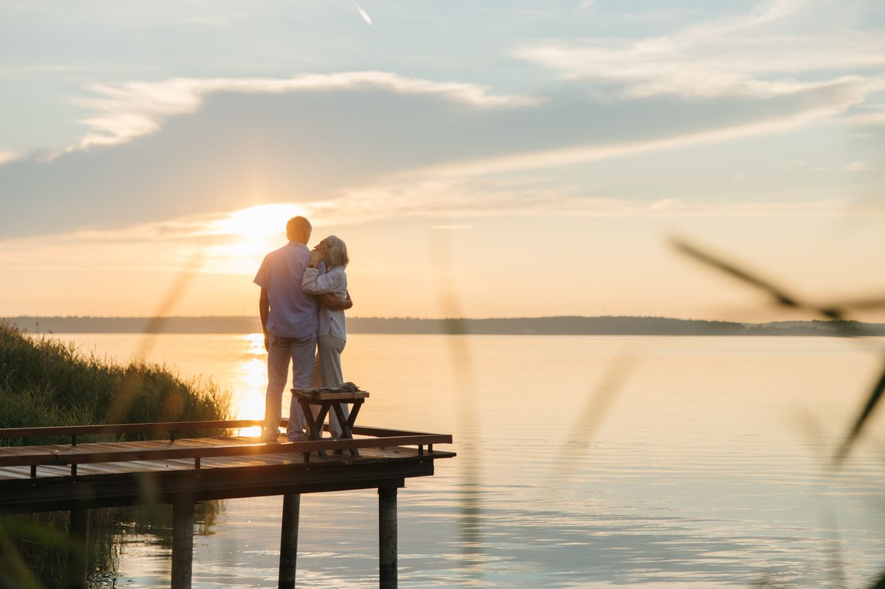 Couple senior sur un ponton au coucher du soleil illustrant le cumul de pensions de retraite internationales