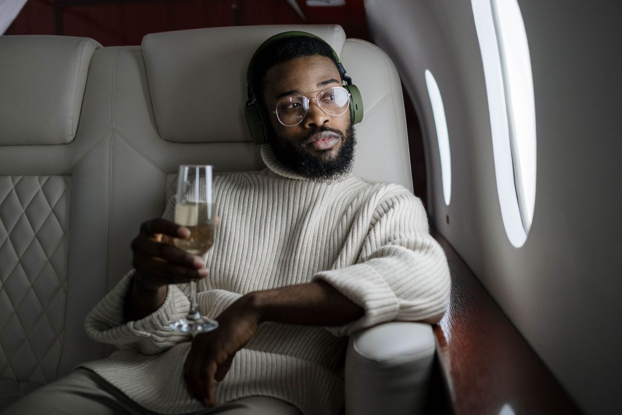 Homme dans un avion avec une coupe de champagne illustrant le choix d’un CGP pour expatrié
