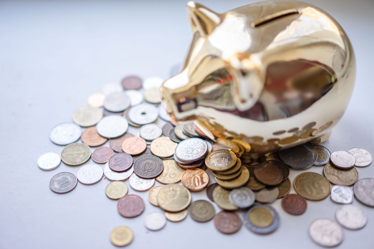 Alt text : Tirelire dorée entourée de pièces illustrant comment investir 100 000 euros quand on est expatrié