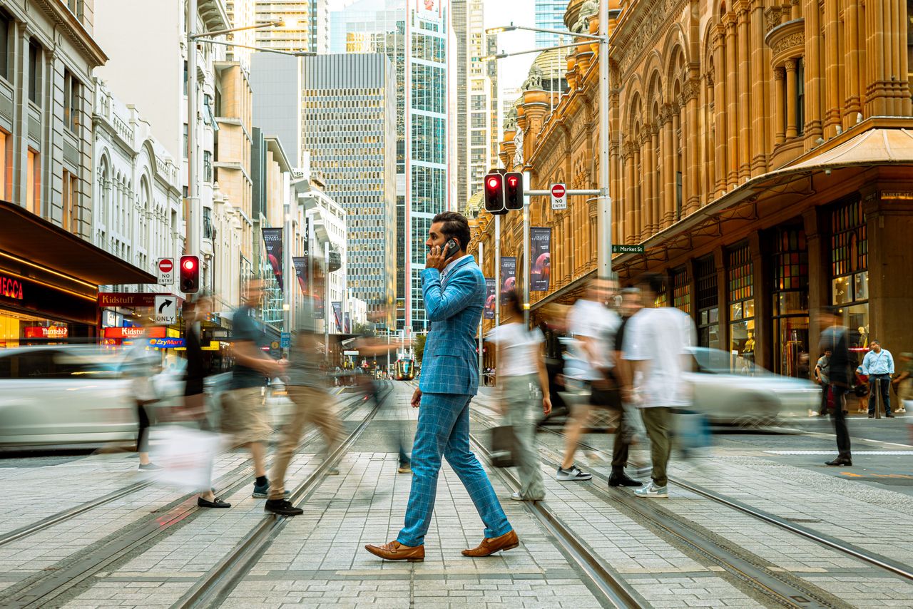Homme d’affaires traversant une rue de Sydney pour illustrer l’épargne salariale et l’expatriation