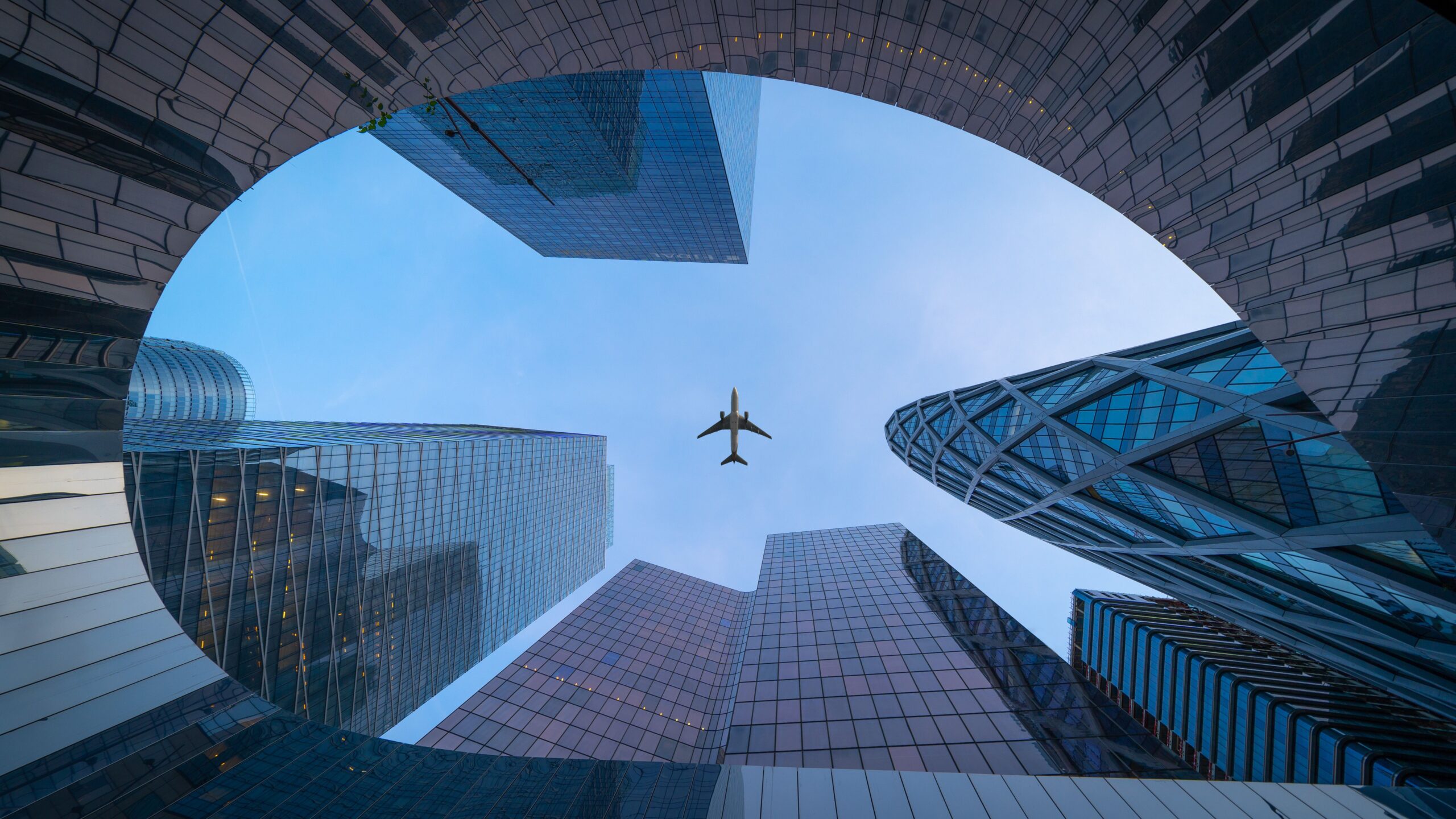 Avion survolant des gratte-ciel modernes pour illustrer la fiscalité des RSU et stock-options à l’expatriation