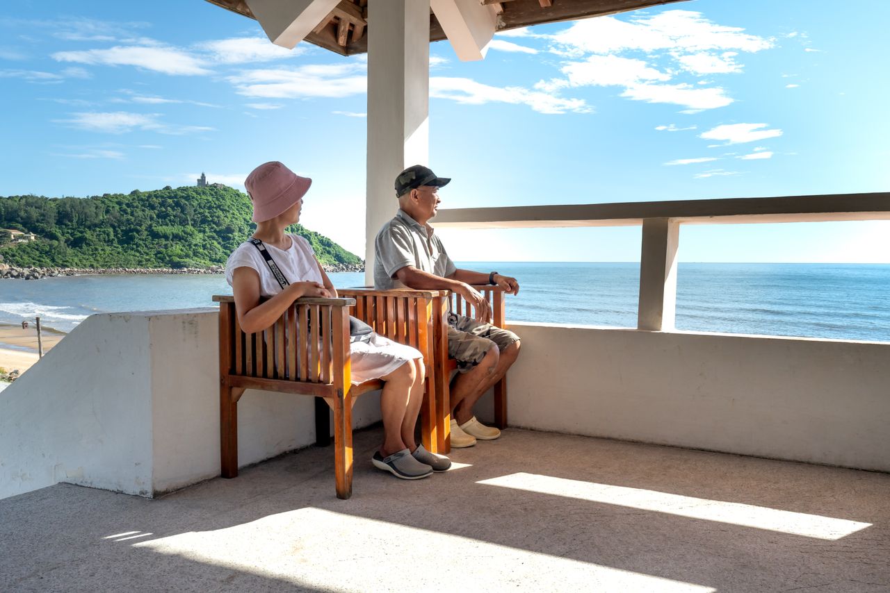 Deux personnes assises face à la mer pour illustrer l’investissement en viager quand on est expatrié