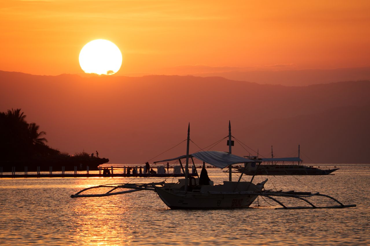 Bateaux traditionnels au coucher du soleil illustrant la fiscalité d’un expatrié français aux Philippines